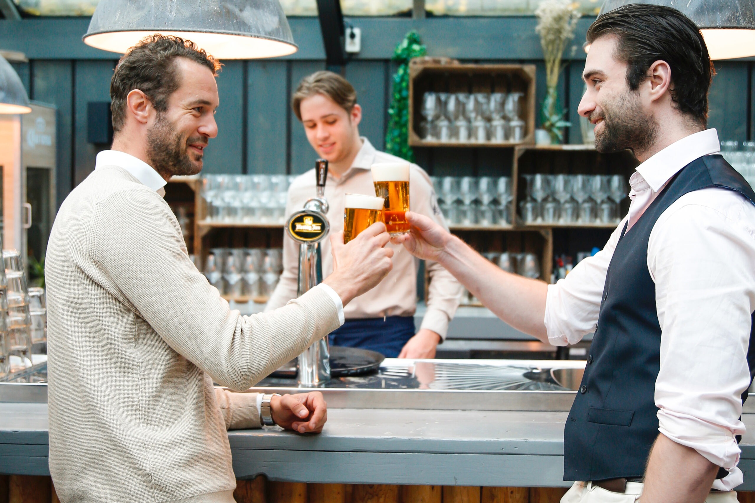 Twee mannen proosten, glas bier, Vondelpark zaal, Amstel Boathouse